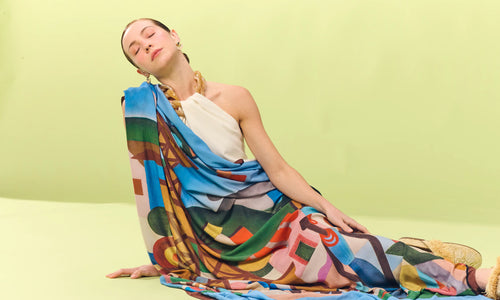 Imagem de modelo vestindo roupa e lenço Scarf Me em fundo verde.