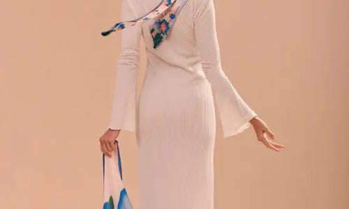 Imagem de modelo de costas com lenço no pescoço e segurando lenço na mão.