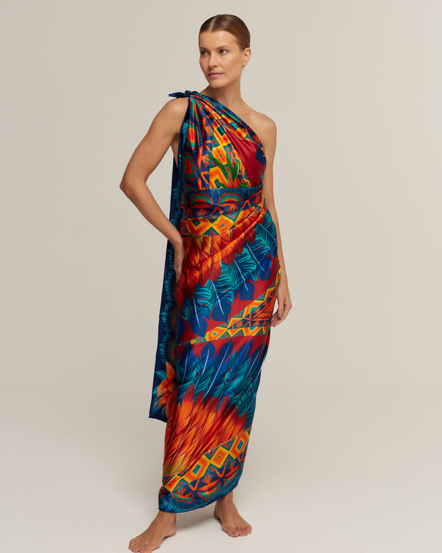 Mulher vestindo lenço panneau longo com estampa colorida posando contra fundo neutro.