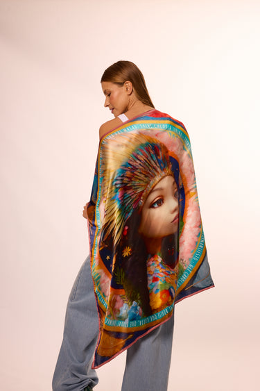 Mulher com lenço brilho de jurema colorido, exibindo imagem artística da indígena com penas. Fotografia de moda com foco no acessório cultural.