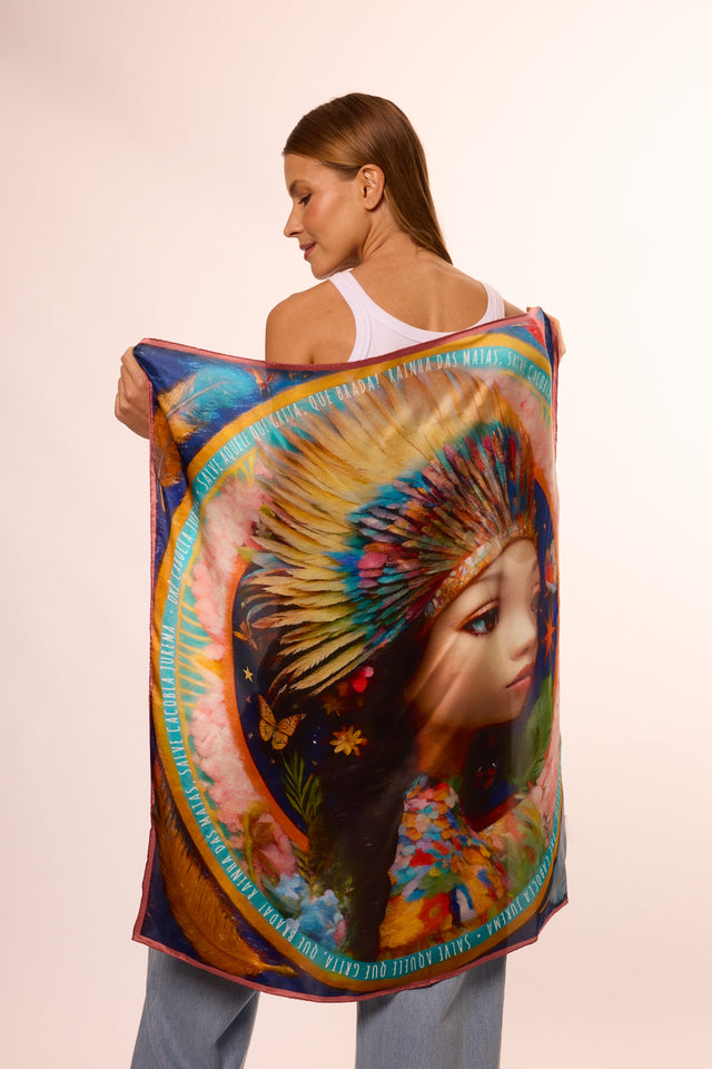 Modelo segurando o lenço brilho de jurema com ilustração de representação de Jurema com penas no cabelo, detalhes florais e borboletas.