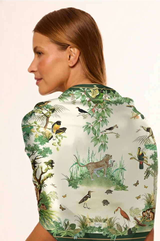 Mulher com cabelo castanho com o lenço para pescoço com estampa de fauna cheia de pássaros, animais selvagens e plantas, capturando um visual elegante e sustentável.