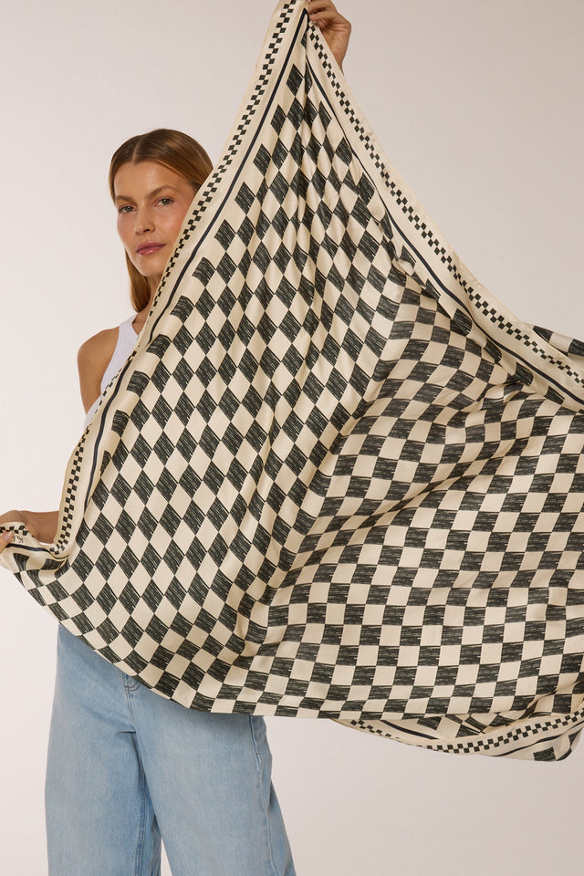 Mulher com cabelo castanho claro e expressão confiante segurando o lenço double face Race, vestindo jeans claro contra fundo branco.