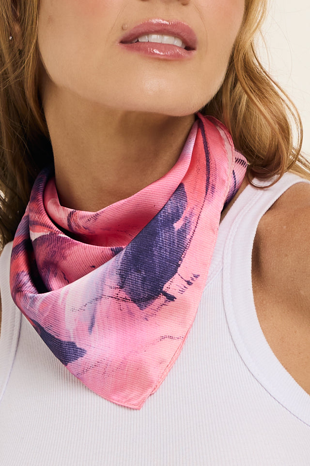 Imagem do lenço vestígios em cetim de seda. O lenço no pescoço da modelo aparece em destaque com seus tons de rosa, azul e branco aparentes.