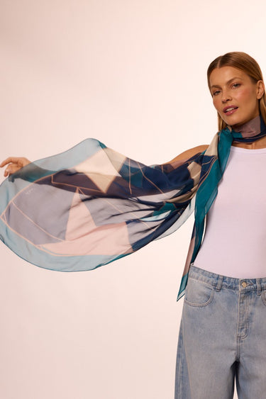 Mulher vestindo lenço no pescoço Pied Gráfico Mousseline. O modelo possui cores verde, azul e pérola.