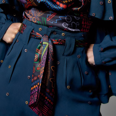Lenço estampado amarrado na cintura de uma calça azul